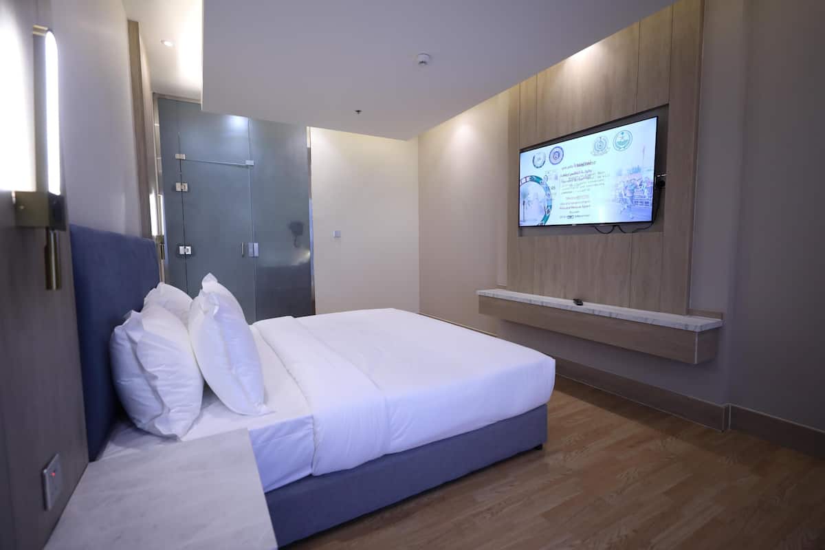 A modern hotel room with a bed, a TV mounted on the wall, and a wooden floor.