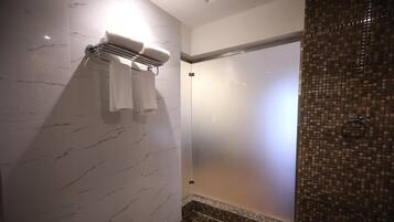 A modern bathroom with a glass shower enclosure, a towel rack, and a marble wall.