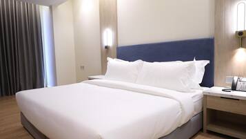 A hotel room with a large bed, a bedside table with a phone, and a wall-mounted light.