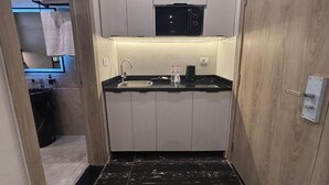 A compact kitchen with a microwave, sink, and countertop. - Deluxe Room at Stay Inn 51 Hotel (2 Adults + 1 Child) (Banī Ghālib)