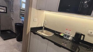 A compact kitchen with a sink, a microwave, and a coffee maker. - Comfortable Twin Room at Stay Inn 51 Hotel (Banī Ghālib)