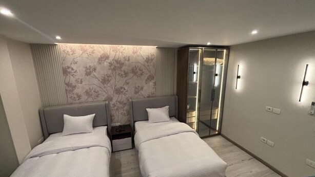 A modern hotel room with two beds, a walk-in closet, and a decorative wall. - Comfortable Twin Room at Stay Inn 51 Hotel (Banī Ghālib)