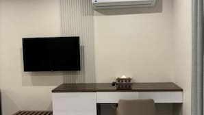 Ein moderner Arbeitsraum mit einem an der Wand montierten Flachbildfernseher, einem Schreibtisch mit Computer und einem Stuhl.