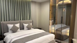 A modern bedroom with a large bed, a glass wardrobe, and a headboard with vertical lines. - Stay Inn 51 Hotel – Cozy Family Rooms for Your Perfect Getaway (Banī Ghālib)