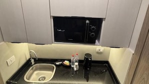 Eine kleine Küchenzeile mit Spüle, Mikrowelle und Kaffeemaschine.