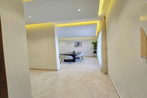 A spacious room with a dining table and chairs, a potted plant, and a painting on the wall. - LP50.2 Livedin Pristine 2BR  Outdoor Space Al Yasmin (Riyadh)
