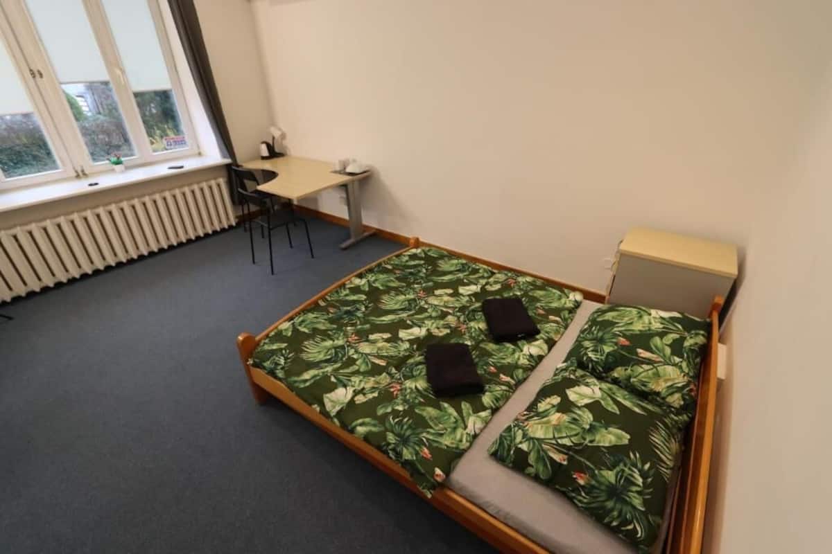 A bedroom with a bed, a desk, and a chair.