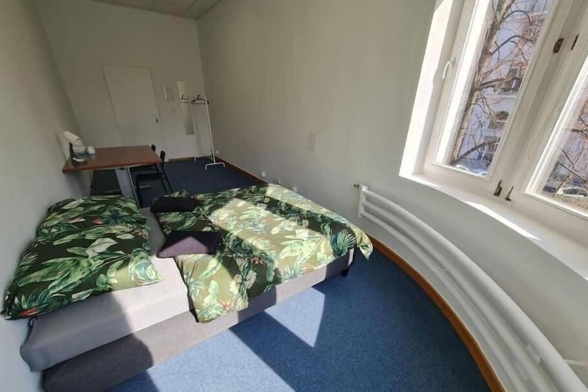 A small room with a bed, a desk, and a window.