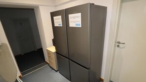 A compact room with a double door refrigerator, a small beige cabinet, and a white door. - Fantastic Inn Warsaw - FMG (Warsaw)