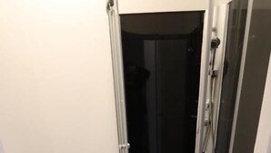 A corner shower with a glass door, white walls, and a tiled floor. - Fantastic Inn Warsaw - FMG (Warsaw)