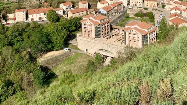 Un village perché sur une colline, doté d’une architecture traditionnelle, d’un imposant beffroi et d’un pont reliant les bâtiments.