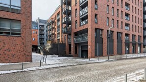 A multi-story building with brick facade, large windows, and balconies. - Modern Studio in Wrzeszcz | Balcony | Close to the Station (Gdańsk)