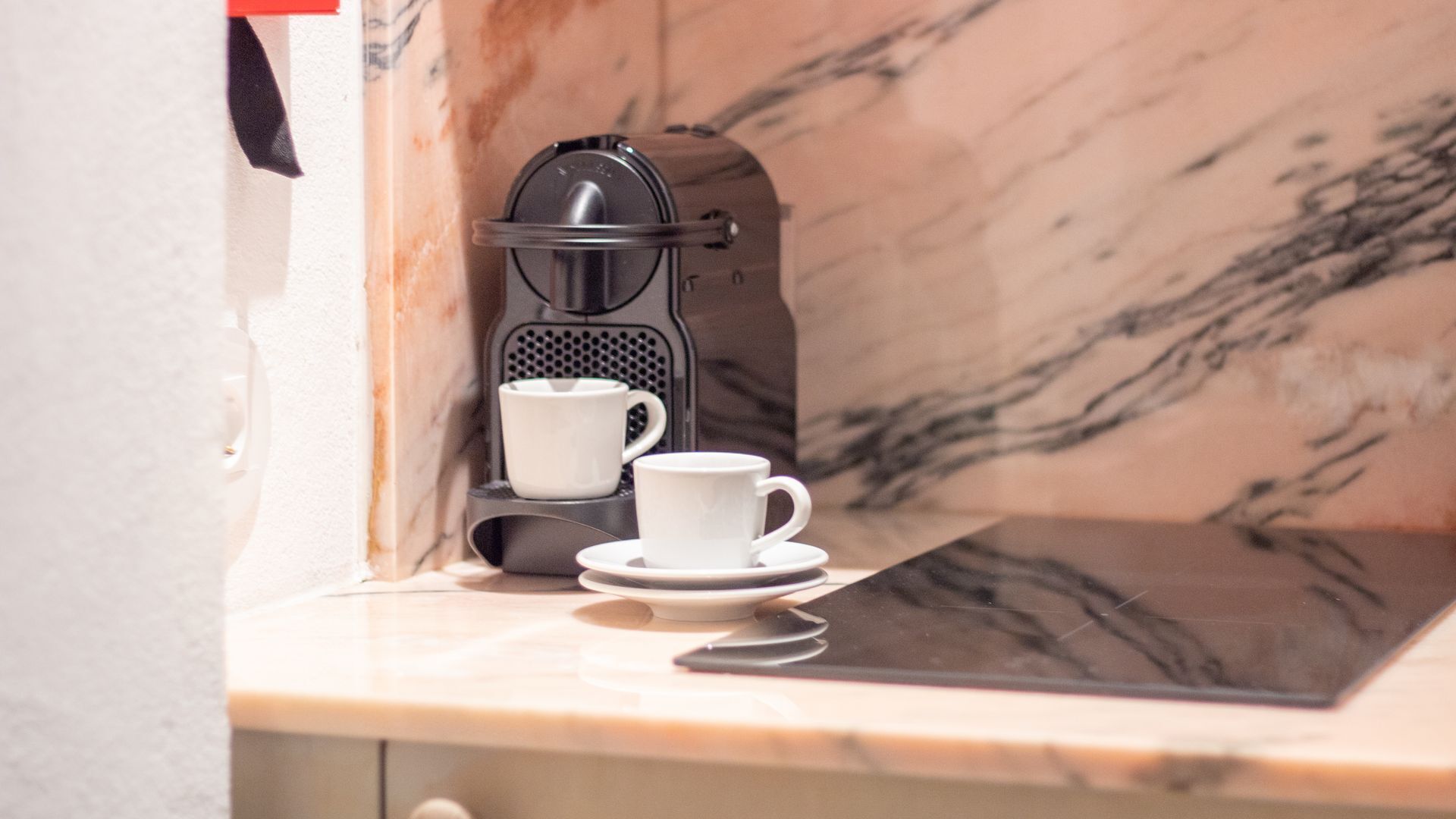 Une machine à café, avec une tasse et une soucoupe, posée sur un comptoir en marbre.