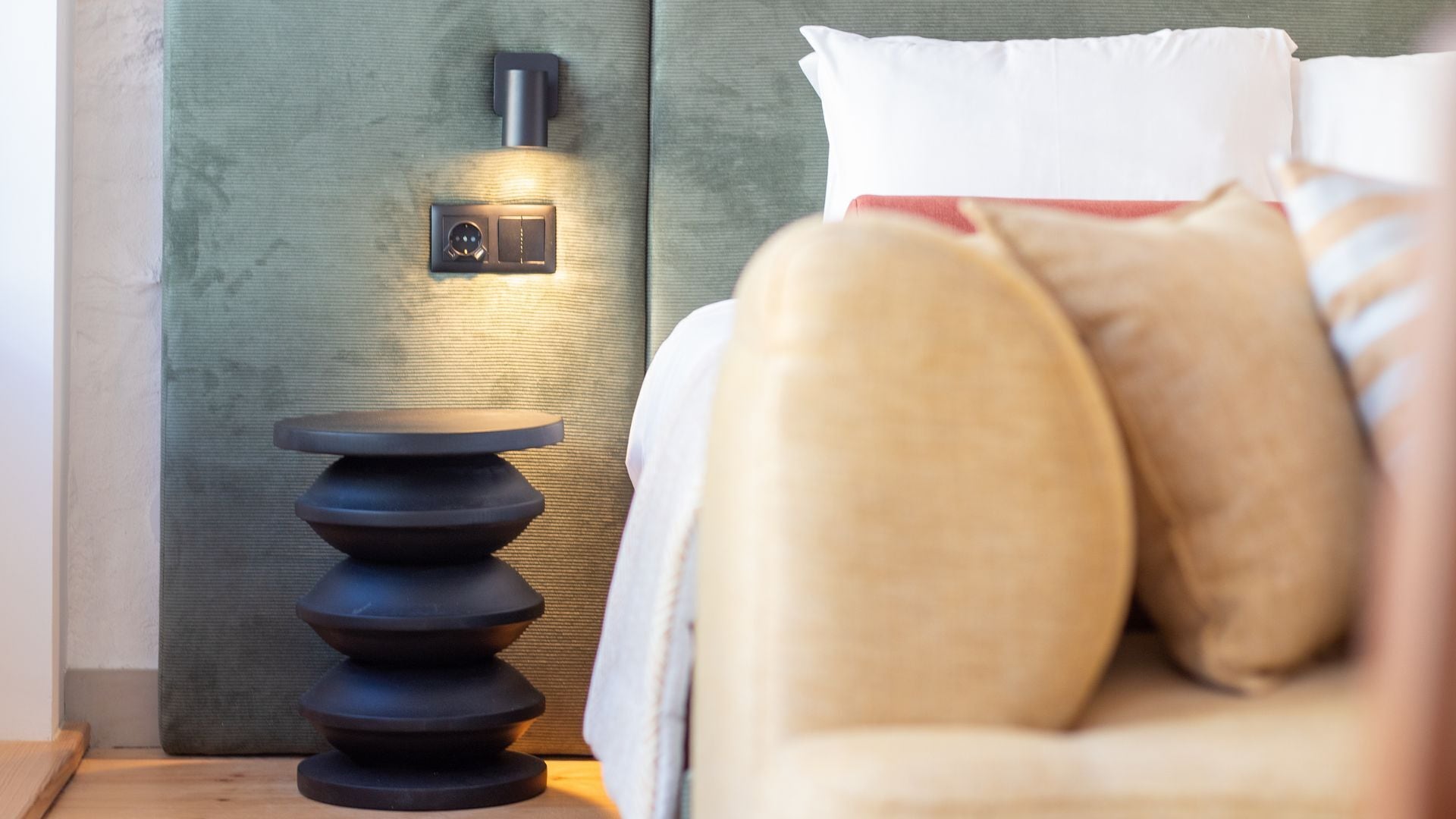 Um quarto moderno com uma cama, uma mesinha de cabeceira e um candeeiro fixado na parede.