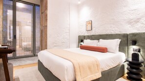 Een slaapkamer met een bed, nachtkastje, lamp en uitzicht door een glazen deur.