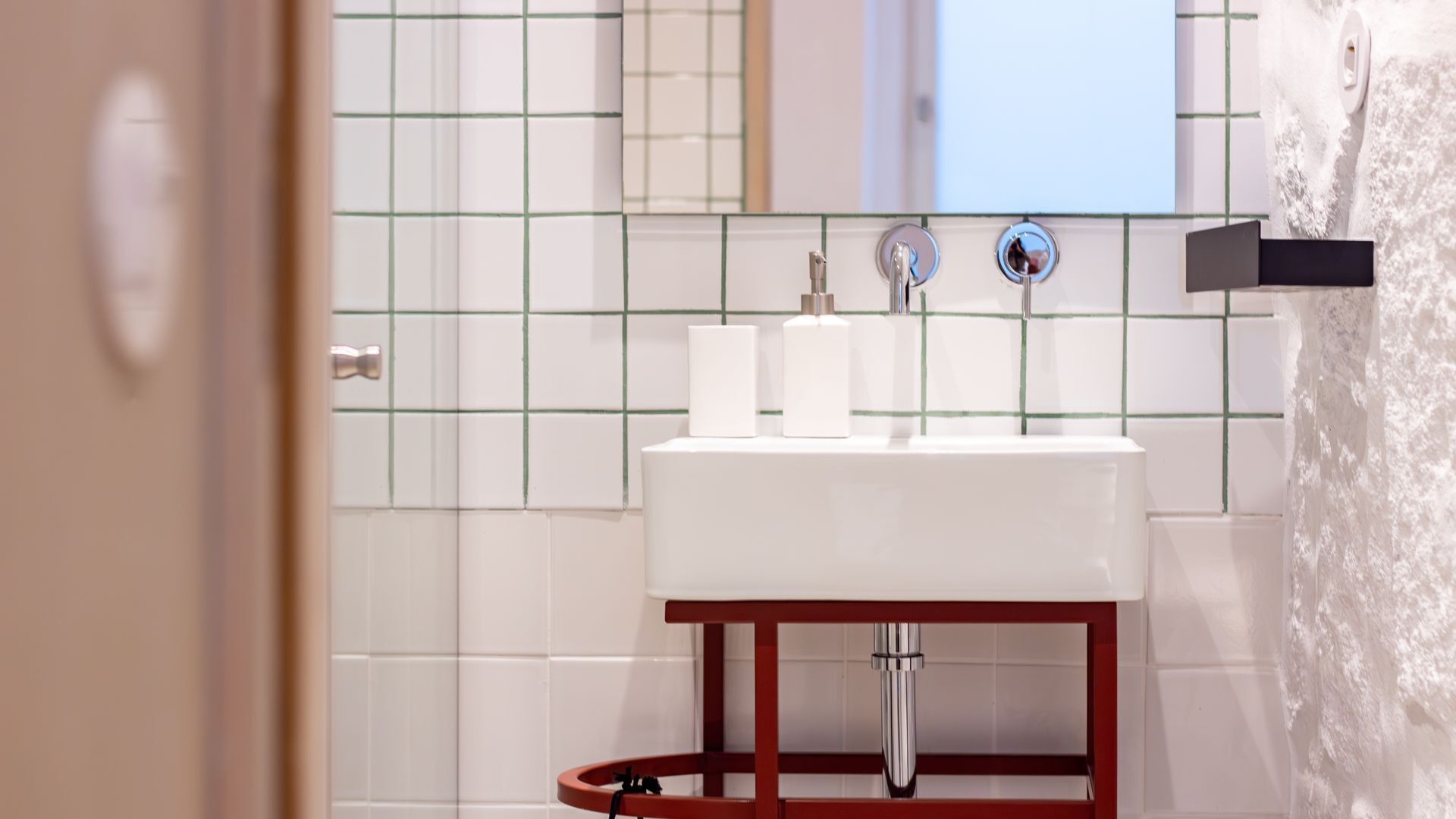 Ein Badezimmer mit einem weißen Waschbecken, zwei Flaschen auf der Ablage und einem Spiegel darüber.