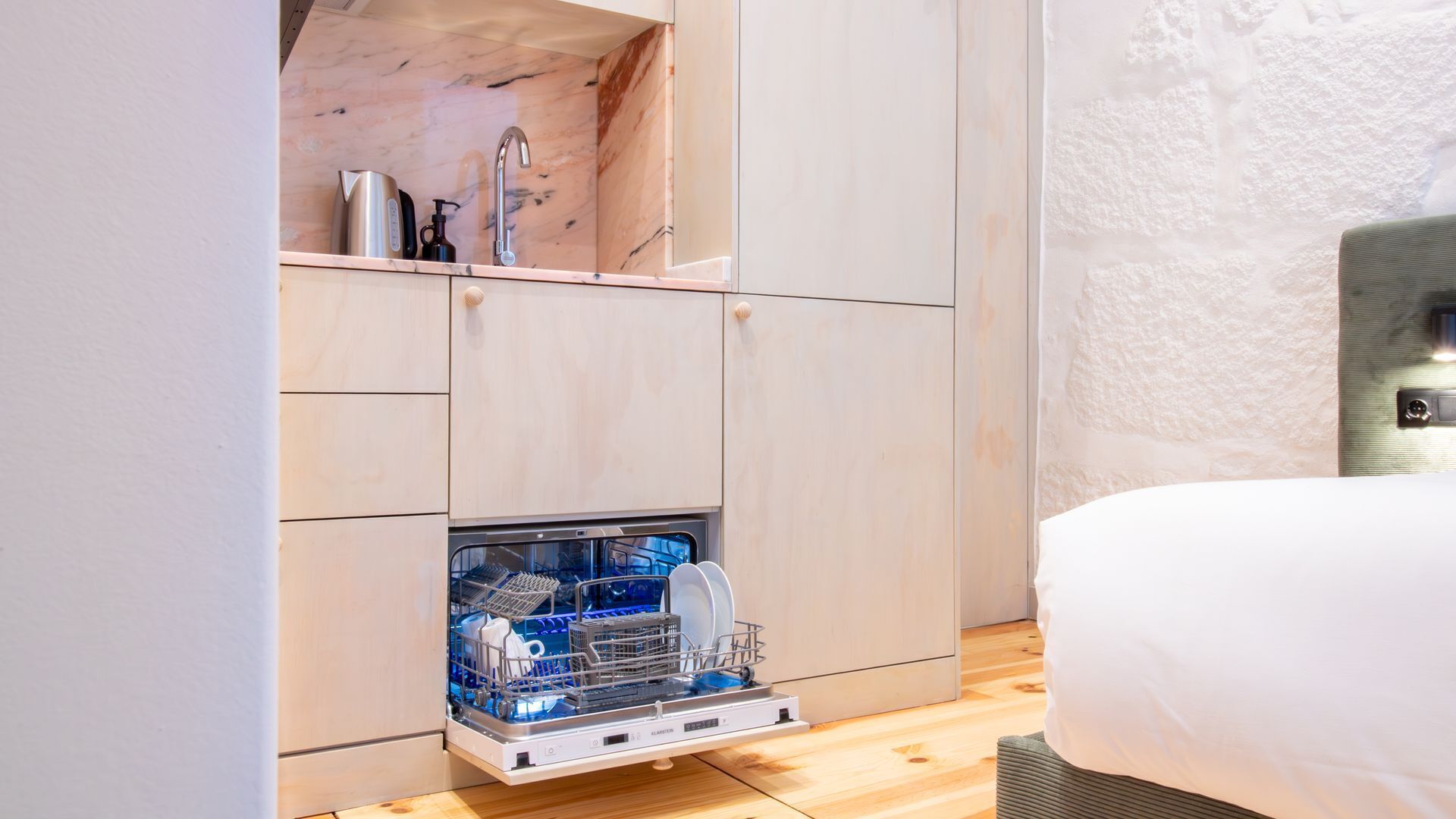 Eine kleine Küche mit Geschirrspüler, Kaffeemaschine und Wasserkocher auf der Arbeitsfläche.