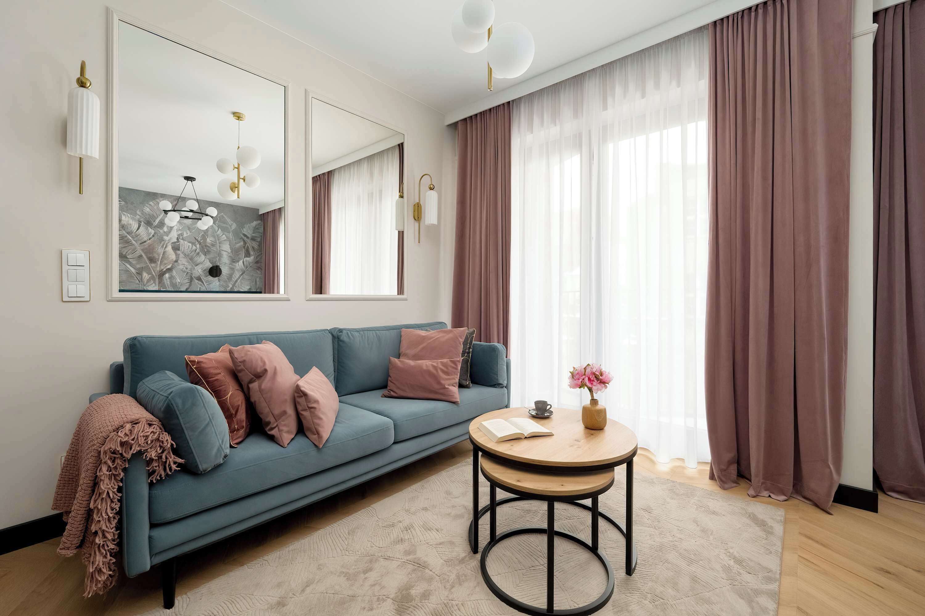 Ein modernes Wohnzimmer mit einer Couch, einem runden Couchtisch und einem großen Spiegel.