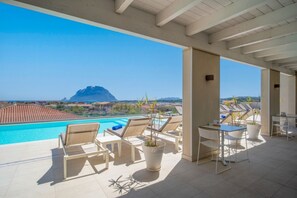 Eine Dachterrasse mit Pool, Liegestühlen und einem Tisch.