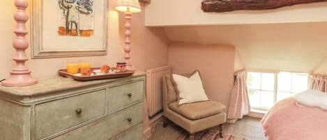 A cozy bedroom with a dresser, a chair, a bed, and a window with curtains.