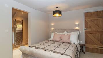 Un dormitorio con una cama, una puerta de madera y una mesita de noche.