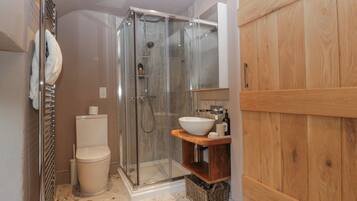 Un baño moderno con ducha de vidrio, inodoro y tocador de madera con lavamanos.