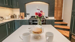 A kitchen with dark green cabinets, a white countertop, a stove, and a vase with flowers. - 26 Frenchgate (Richmond)