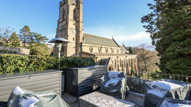 A historic building with a tall tower, surrounded by greenery and covered outdoor furniture. - 26 Frenchgate (Richmond)