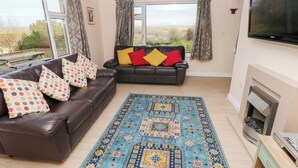 A living room with two sofas, a patterned rug, a fireplace, and a TV. - Cherry Trees (Haverfordwest)