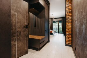 A modern interior with a bench, a brick accent wall, and a view to a room with a bed and window. - Walonska 19 - Luxury Loft Apartment (Wrocław)