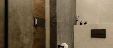 A modern bathroom with a toilet, a wooden door, and a towel rack.