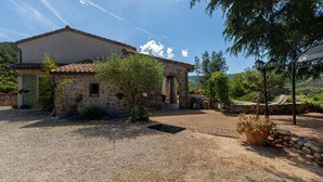 Une maison en pierre avec une allée gravillonnée, un petit jardin et une vue sur le paysage environnant.