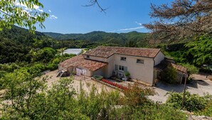 Une maison avec un toit en tuiles, entourée de verdure et de collines.