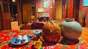 Une pièce traditionnelle, avec des murs en bois, comprenant une grande table recouverte d’une nappe à motifs floraux, un grand vase en céramique et un buffet en bois.