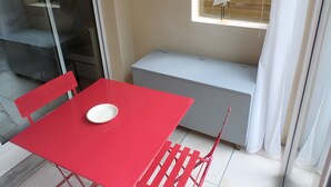 Ett rött bord med en vit tallrik, en vit bänk och ett fönster med en vit gardin.