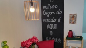 A dining area with a blackboard, red chair, and a wooden table with red plates. - Studio in Butantã, near USP. (São Paulo)