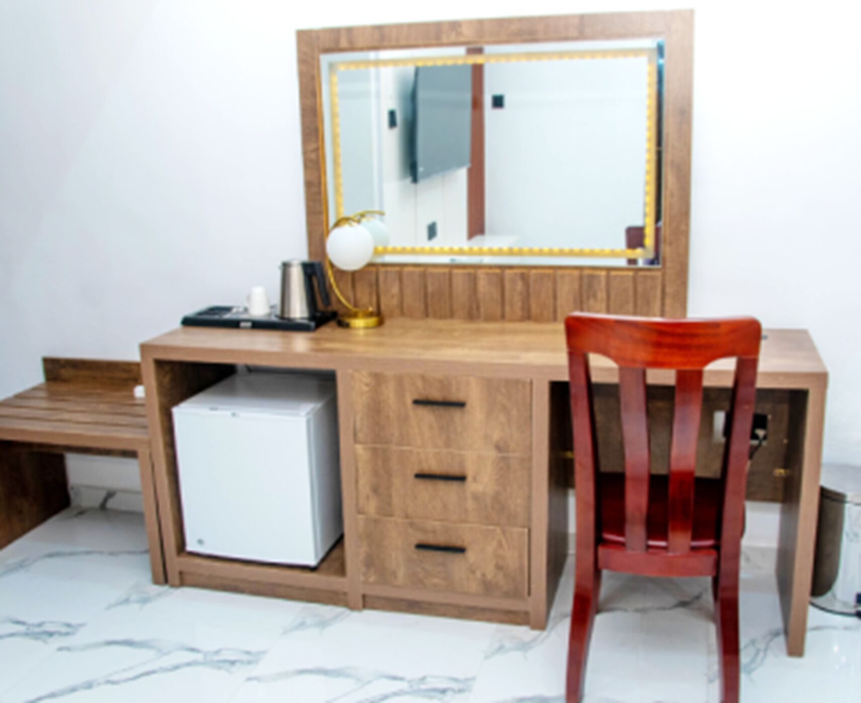 Un bureau en bois, avec un miroir, une lampe et une chaise.