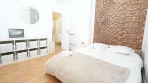 Ein Schlafzimmer mit einem Bett, einem Schminktisch, einem Spiegel und einer Wand mit Muster.