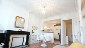 Ein modernes Wohnzimmer mit Kamin, Essbereich und einer Küche im Hintergrund.