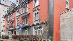 A multi-story residential building with balconies, a garage door, and a no parking sign. - Premium studio in city center - Color 3 (Zürich)