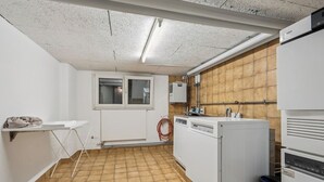 A compact kitchen with a washing machine, a drying rack, and a window. - Premium studio in city center - Color 3 (Zürich)