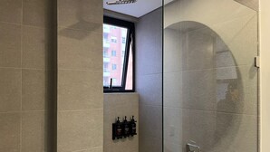 Une salle de bain moderne avec une douche à parois de verre, une fenêtre et un ensemble de produits de toilette.