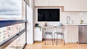 A modern kitchen with a large window, a flat-screen TV, and a compact refrigerator. - w Beautiful Loft in the Heart of Bogot (Bogotá)