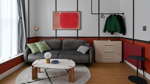 A modern living room with a grey sofa, a white coffee table, and a red abstract painting on the wall. - Stylish 1-bed Apartment Near Angel Station (London)