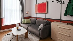 A modern living room with a grey sofa, a white coffee table, a beige dresser, and a red abstract painting on the wall. - Stylish 1-bed Apartment Near Angel Station (London)
