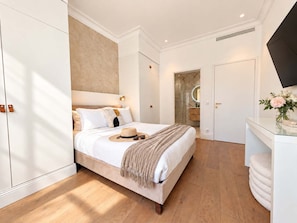 A modern bedroom with a large bed, a vanity with a mirror, and a flat-screen TV mounted on the wall. - Scarlett - 4 Bedroom next to the Croisette (Cannes)