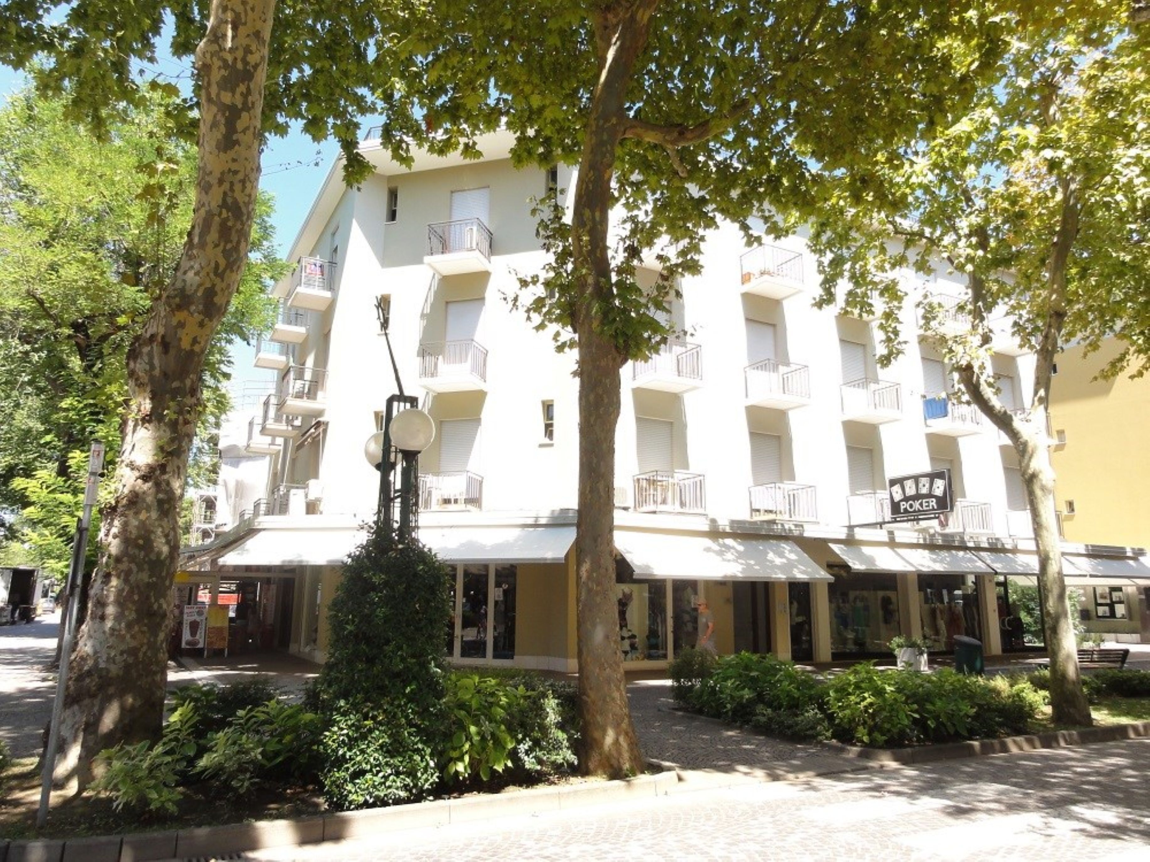 Un hôtel à plusieurs étages doté de balcons, d’une enseigne bien visible indiquant l’emplacement d’une salle de poker et d’un jardin bien entretenu.
