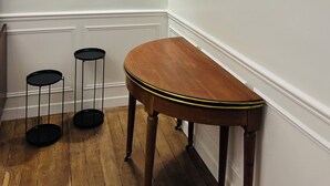En hall med en träbänk, en rund spegel och två svarta golvlampor med modern design.