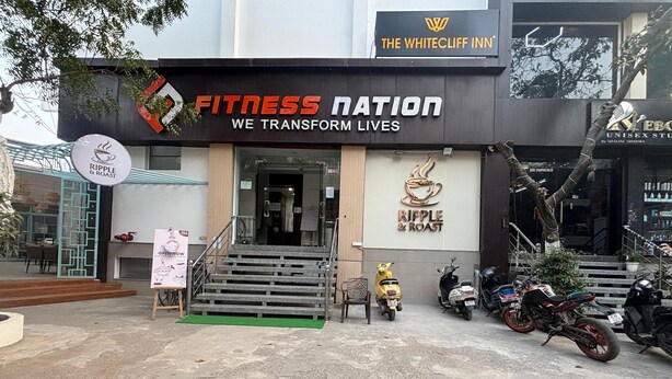 Um centro de fitness chamado 'Fitness Nation', com uma placa para 'Ripple & Roast' e uma oferta de '25% de desconto'.