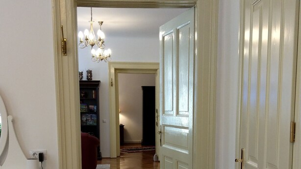Une chambre à coucher comprenant un lit, une table de chevet, une lampe, une commode et une porte donnant sur une autre pièce.